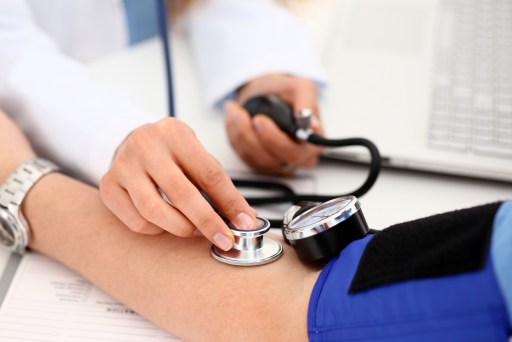 A person having their blood pressure checked with a stethoscope